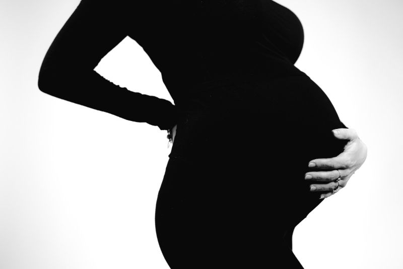 Can you see a chiropractor while pregnant - a pregnant woman holding her back and belly.